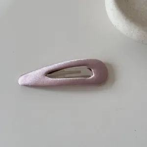 Vista dettagliata di un fermaglio per capelli in raso rosa tenue con riflessi eleganti