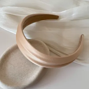 Close-up of a beige padded headband showing the elegant satin texture and double ridge.