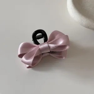 Primo piano di un elegante fermaglio per capelli a fiocco in raso rosa su bianco