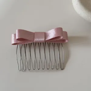Vista dettagliata di un dolce pettine per capelli con doppio fiocco in nastro rosa