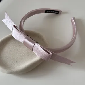 Dettaglio della fascia in raso rosa con etichetta fatta a mano e morbida trama di seta