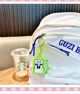 Close-up of a panda flip-animation keychain hanging on a white backpack