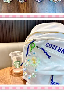 Close-up of handmade beaded moon and girl charm hanging on a white backpack