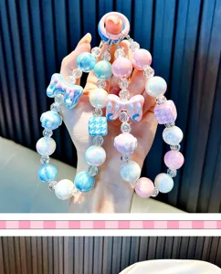 Gedetailleerd zicht op iriserende kralen telefoonhanger met roze en blauwe strikjes.