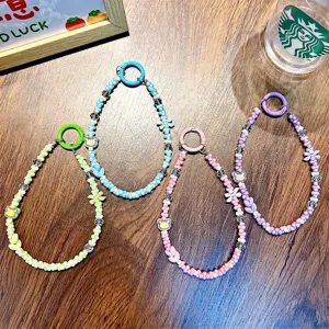 Colorful beaded bear phone straps with carabiner clips on a wooden background surface
