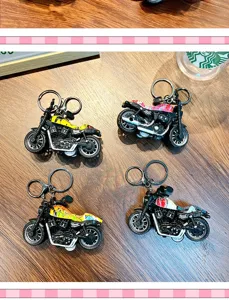 Détails de quatre mini porte-clés moto colorés à friction sur une table en bois