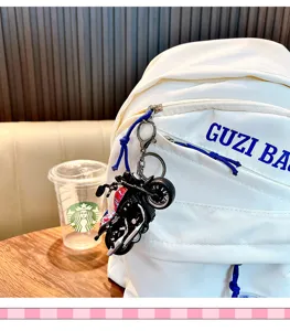 Détail d'un porte-clés mini moto noir accroché à la fermeture d'un sac à dos blanc