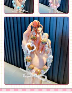 Gros plan d'un charme de téléphone en perles colorées fait main avec nœud et cœur pixel