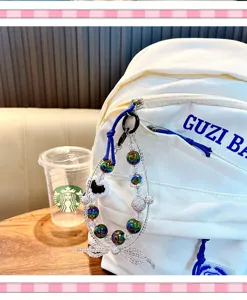 Gros plan d'un charme en perles irisées avec nœud suspendu à un sac à dos blanc