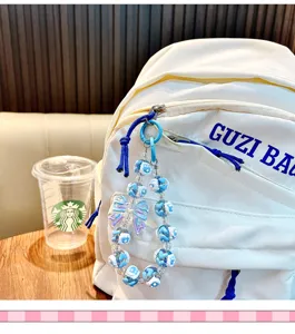 Detailansicht eines blau-weißen Perlen-Schlüsselanhängers mit Schleife am Rucksack