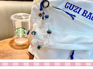 Close-up of a decorative crystal butterfly beaded keychain charm on a white backpack