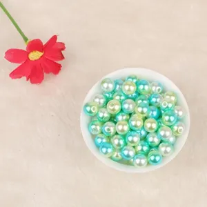 Dettaglio di perle finte in ABS sfumate blu e verdi in una ciotola bianca.