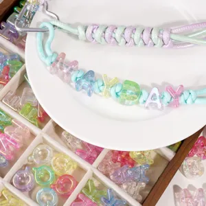 Macro view of iridescent acrylic letter beads spelling MAYDAY on a pastel braided strap