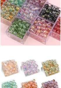 Gros plan de perles en verre colorées avec poussière d'or dans des boîtes transparentes.