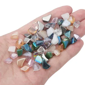 Assorted colorful irregular glass beads held in hand for scale and texture detail.