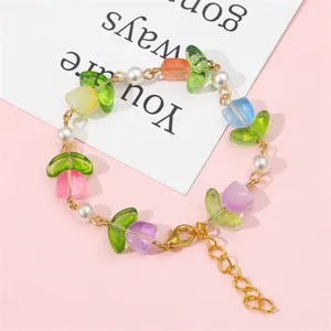 Detailansicht eines Armbands mit bunten matten Tulpenperlen und Perlen auf rosa Hintergrund