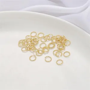 Primer plano de anillas retorcidas bañadas en oro de 14K para joyería artesanal DIY.