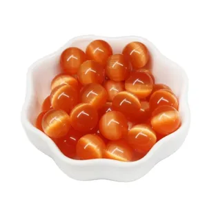 Cuentas redondas de ojo de gato naranja para hacer joyas de bricolaje en un plato de cerámica