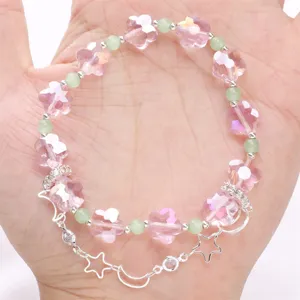 Nahaufnahme von rosa Blumenperlen-Armband mit Stern-Mond-Sicherheitskette auf der Hand.