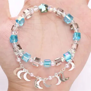 Detaillierte Ansicht eines Kristallarmbands mit silbernen Mondanhängern und weißen Perlen.