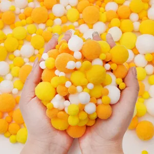 Primer plano de pompones suaves de colores amarillo naranja y blanco para manualidades DIY