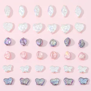 Grid of iridescent heart and butterfly shaped acrylic beads for DIY jewelry making.