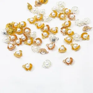 Gros plan de breloques décoratives en forme de coquillage en or et argent avec perles pour bijoux.
