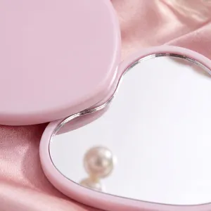 Macro view showing the smooth edges of a pink heart-shaped portable vanity mirror.
