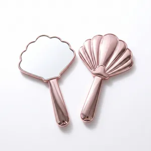 Makro-Detailansicht des roségoldenen muschelförmigen Handspiegels von vorn und hinten