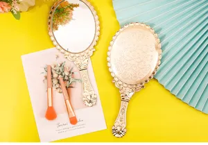 Detailed view of vintage gold handheld mirror with elegant floral embossed patterns