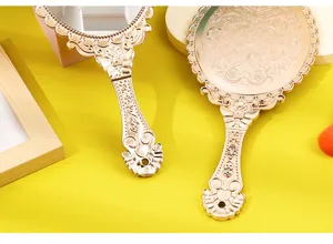 Detailed macro view of the intricate floral engraving on the golden handheld mirror