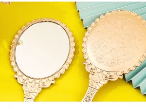 Close-up of vintage gold handheld mirrors showing front mirror and embossed back pattern
