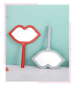 Close-up detail of two stylish lip-shaped handheld makeup mirrors in red and grey colors