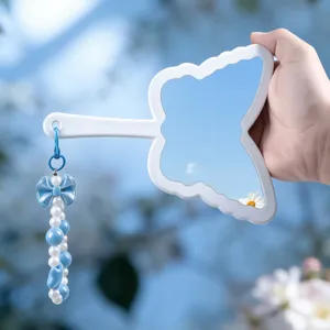 Close-up detail of butterfly shaped handheld mirror with blue pearl bow charm hanging