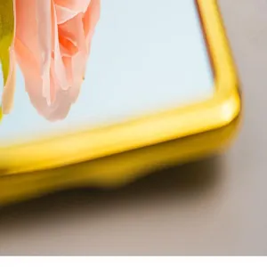 Macro view showing the gold electroplated frame and clear reflection of a makeup mirror.