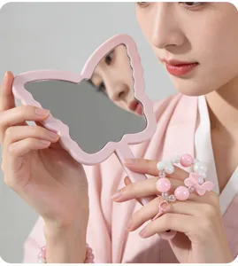 Detailed view of a pink butterfly-shaped handheld makeup mirror with a cute beaded charm