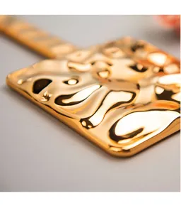 Macro detail of a gold electroplated handheld mirror showing wavy metallic texture.