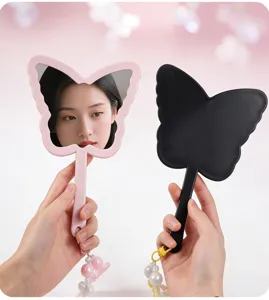 Close-up of pink and black butterfly-shaped handheld mirrors with decorative pendants.