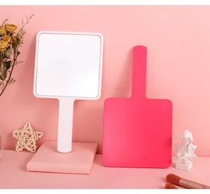 Detailed view of white and pink handheld square makeup mirrors in a gift set scene