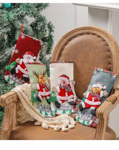 Set of four large burlap Christmas stockings with 3D appliques displayed on a vintage chair