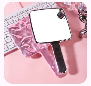 Dettaglio del retro rosa a trama ondulata di uno specchio da trucco portatile a mano