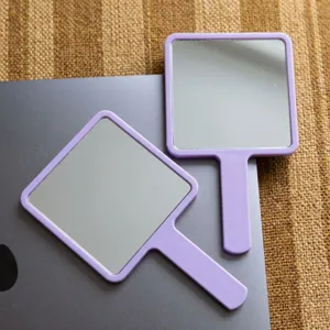 Vue détaillée de deux miroirs de maquillage carrés violets portables avec poignées.