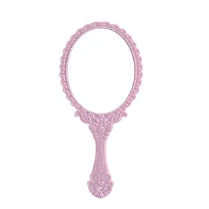 Pink vintage-style plastic hand mirror with ornate floral patterns on white background