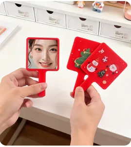 Detail of festive square handheld makeup mirrors with Christmas illustrations and reflection.