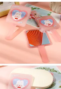 Detail of pink handheld makeup mirror with cute rabbit heart design and frosted finish.