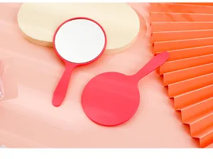 Detailed macro view of round handheld makeup mirror showing front mirror and red back