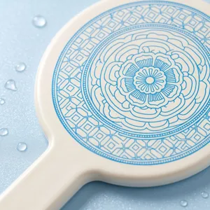 Detailed macro view of the intricate blue floral pattern on a white handheld mirror.