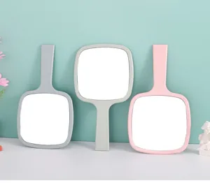 Draagbare handspiegels voor make-up in grijs, beige en roze op een blauwgroene wand