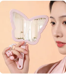 Close-up of a pink butterfly-shaped handheld makeup mirror with a beaded handle charm.