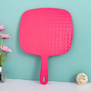 Detailweergave achterkant van een roze grote handmakeup spiegel met rasterpatroon.